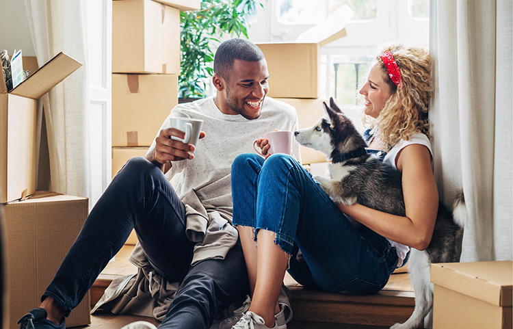 Jeune couple avec son chien, prenant une pause pendant qu’il aménage dans sa nouvelle maison