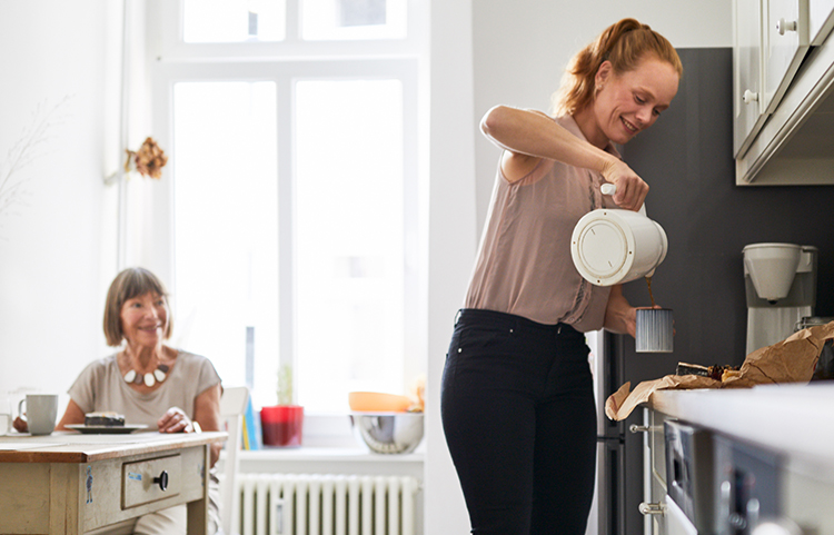 Middle-aged woman pouring tea for her elderly mother